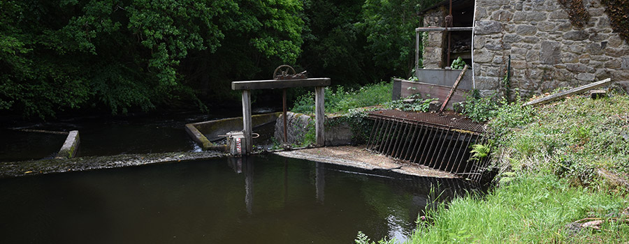 Gros plan sur une partie d'un moulin avec à l'avant une rivière