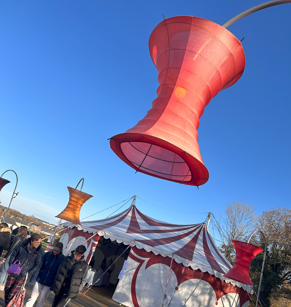 Une grande lanterne rouge au premier plan. Derrière un chapiteau de cirque