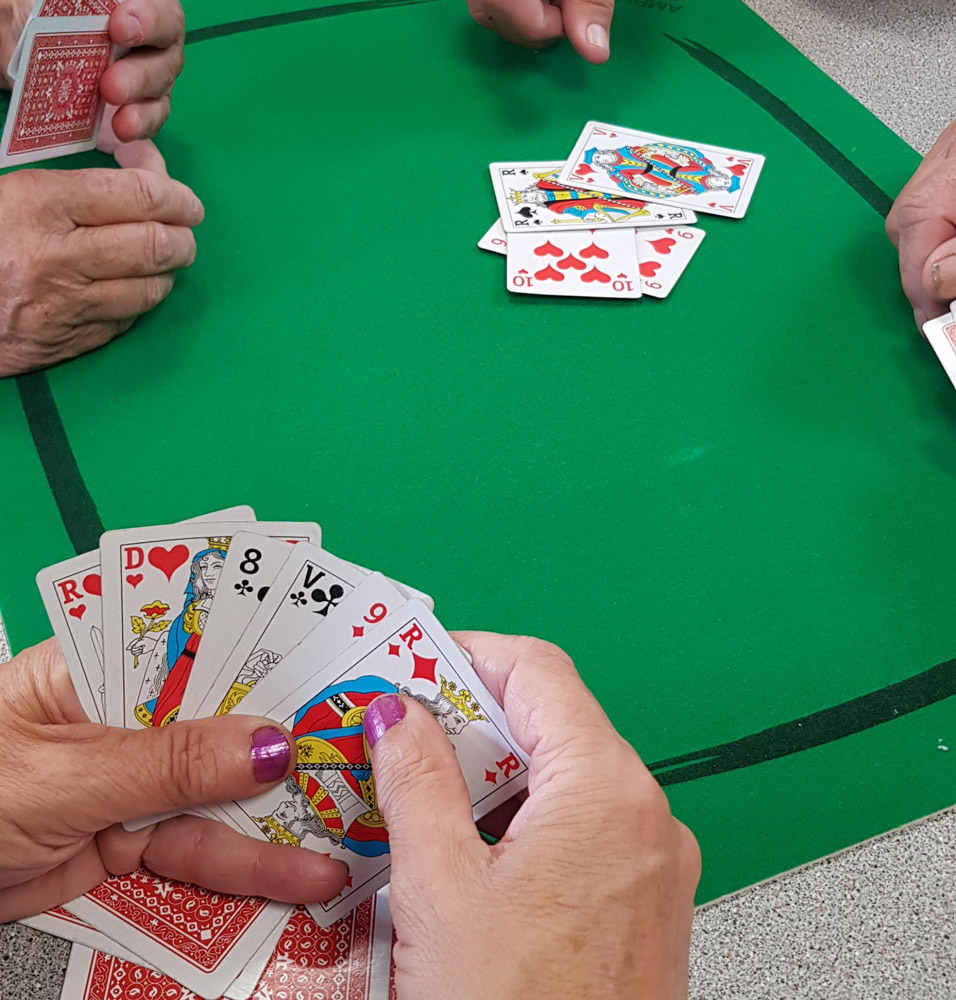Des mains qui tiennent des cartes sur un tapis vert