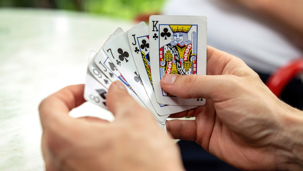 Gros plan sur des mains tenant des cartes à jouer