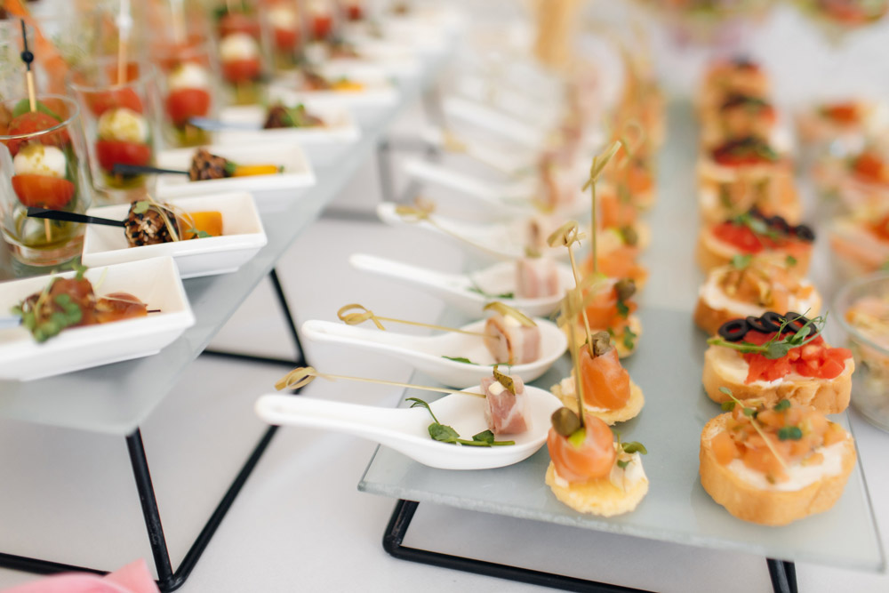 Assortiment de verrines et de bouchées apéritives disposées sur un buffet, avec des toasts au saumon et des mini-brochettes.