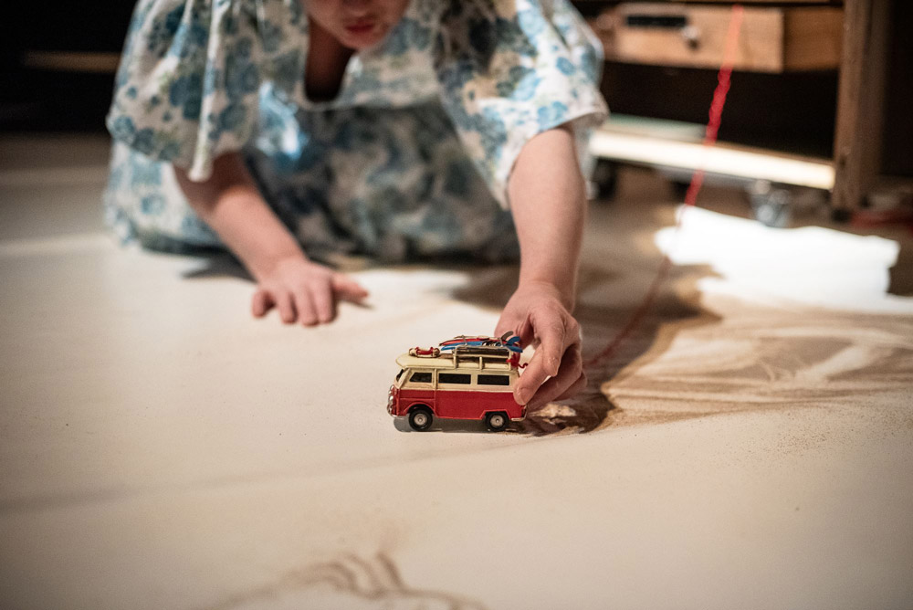 Un femme en robe jouant avec une petite voiture